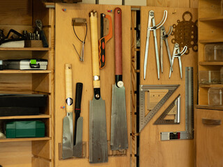Above the carpenter's table, on the wall, there are shelves with various carpentry tools.