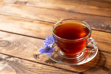 a glass mug with a chicory drink. A blue chicory flower floats in a cup with a drink