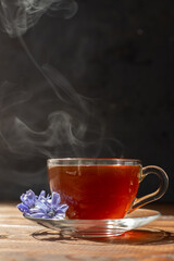 a glass mug with a chicory drink. A blue chicory flower floats in a cup with a drink