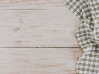 Kitchen napkin on a wooden table.
A checkered kitchen napkin lies on the right on a wooden table with space for text on the left, flat lay close-up.