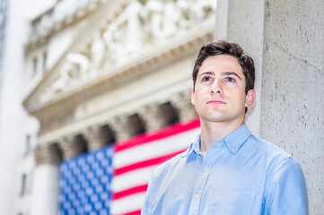 A young guy is sincerely looking forward. There is American flag in the background.