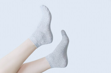 Legs of a Caucasian woman in gray cotton socks on white background.