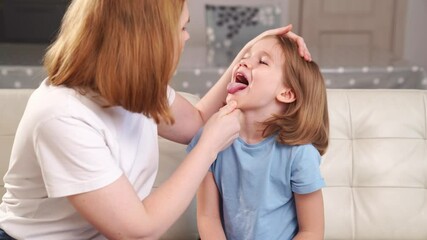 the little girl complains of a sore throat and her mother examines it. 