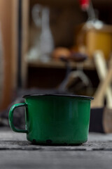 Old metal mug. Enamel cup. On the kitchen table