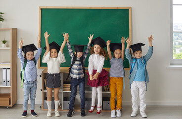 Kids graduate. Portrait of funny little kindergarten or junior high school graduates who are...