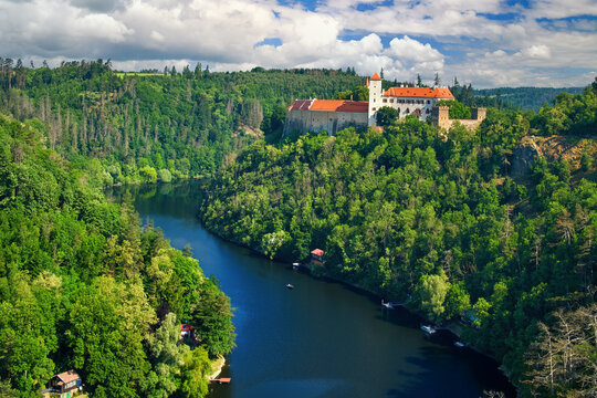 Old Moravian castle, standing on a rock promontory above the river Dyje against a summer blue sky with white clouds, surrounded by green forest. Tourist area. Aerial view of B&iacute;tov castle, Czechia.