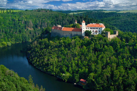 Old Moravian castle, standing on a rock promontory above the river Dyje against a summer blue sky with white clouds, surrounded by green forest. Tourist area. Aerial view of B&iacute;tov castle, Czechia.
