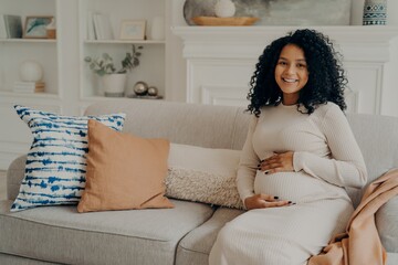 Smiling pretty black expectant young mom feeling relaxed and enjoying pregnancy