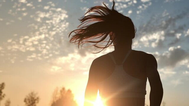 Woman jogger running outdoor at yellow sunset cloud sky enjoying morning physical activity