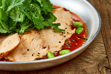 Grilled chicken breast with tom yam sauce and parsley on a wooden background. Close up, selective focus