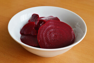 Red beet salad in bowl on wooden background