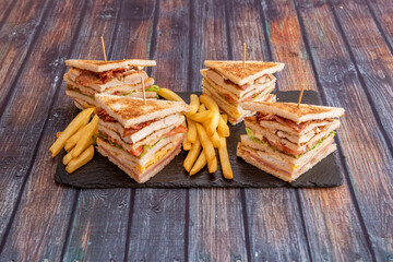 Great club sandwiches with lots of bacon-filled flats, fried eggs, lettuce, cheese, ketchup, ham, chicken fillets and a side of French fries.