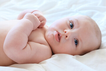 Close-up Portrait of a beautiful Baby on white. Head and Face. Newborn Baby lying on its side and looks into the Camera. Motherhood, health, pediatrics concept. Cute and adorable Infant