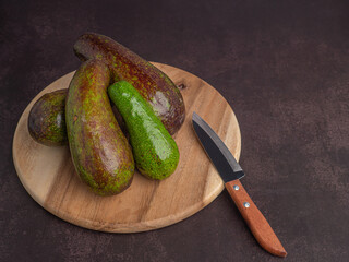 Avocados on a wood cutting board with a knife on a wooden table. Top view. Flat lay, space for text. Healthy fruits concept