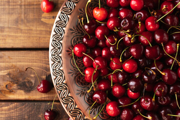 a lot of ripe cherries are lying on a copper tray with a pattern.