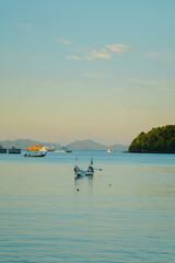 Longtail mooring with a sunset. Holiday lifestyle landscape with skyline sailboat and sunset twilight. Yachting tourism - maritime evening walk. Romantic trip on luxury yacht during the sea sunset.