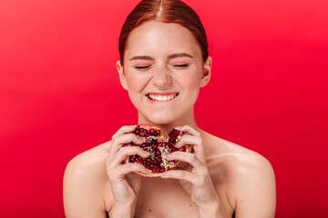 Beautiful girl with fresh garnet laughing with closed eyes. Studio shot of smiling amazing woman...