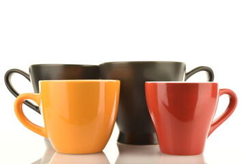 Four ceramic cups of different colors, close-up, isolated on white.
