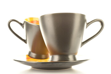 Two ceramic cups of black color on a saucer, close-up, isolated on white.
