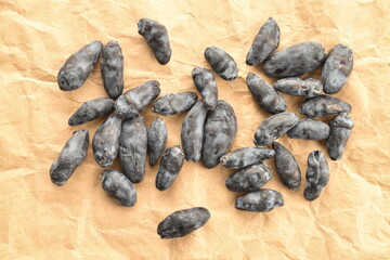 Several dark blue organic ripe honeysuckle berries on craft paper, close-up, top view.
