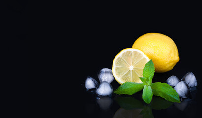 Ripe, juicy lemons and pieces of ice on the black background. Making lemonade. Preparation refreshing summer drink. Close-up. Copy space.