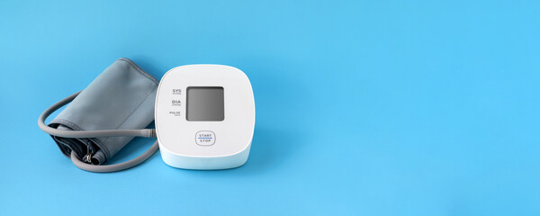 Automatic blood pressure monitor on blue background. Medical electronic tonometer. Wide panoramic...