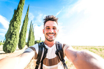 Happy man with backpack taking selfie hiking in the nature - Young guy smiling at camera - Hipster...