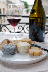 Tasting of burgundy red wine from grand cru pinot noir  vineyards with french goat cheeses and view on old town street in Burgundy wine region, France