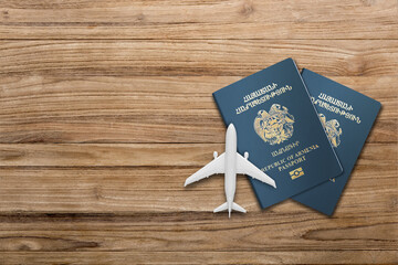 two Armenian  passport and airplane model on a wooden board 