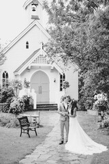 bi racial couple kissing in garden in front of chapel black and white