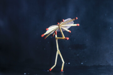 A matchstick man with a matchstick umbrella in the rain. Raining concept. Matchstick art photography used matchsticks to create the character.