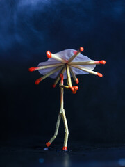 A matchstick man with a matchstick umbrella in the rain. Raining concept. Matchstick art photography used matchsticks to create the character.