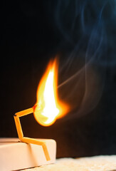 Concept of weakness, sadness, and loneliness. Image of a man-made matchstick. Burning matchstick man sitting alone without a partner. Matchstick art photography.