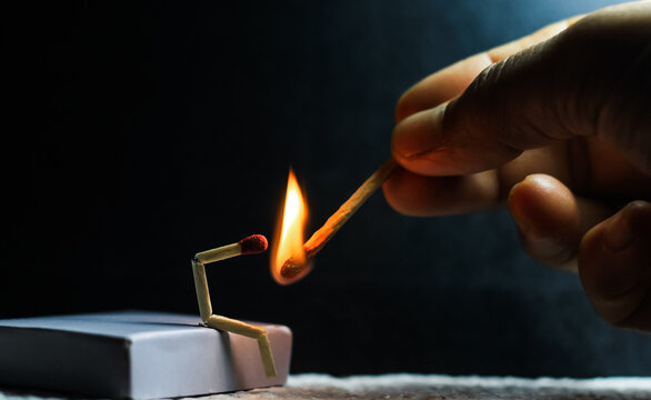Concept of weakness, sadness, and loneliness. Image of a man-made matchstick. Burning matchstick man sitting alone without a partner. Matchstick art photography.
