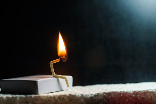 Concept of weakness, sadness, and loneliness. Image of a man-made matchstick. Burning matchstick man sitting alone without a partner. Matchstick art photography.