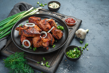 Fried meat with onions and herbs on a dark gray background. Kebab, barbecue.