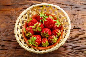 Fresh large strawberries on a wooden table in a wicker dish.