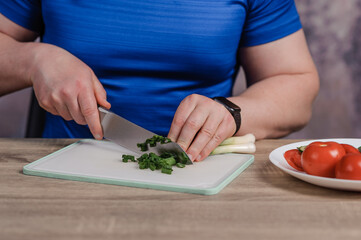 A man cuts green onions on a board. Healthy eating