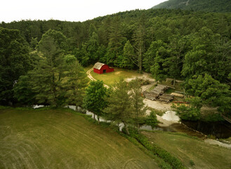An aerial view of a red barn and sawmill by a mountain stream in western North Carolina, USA.