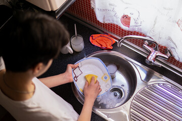 Teenager boy washing dishes at home