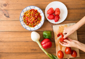 Detail of a woman's hands peeling tomatoes with a knife