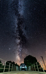 Night shot of 4x4 car and narrow bridge under the milky way