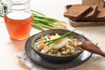 Russian summer okroshka soup with kvass. Freshness okroshka made of summer vegetables, cucumber, radish, potato, boiled eggs, onion. Close up.