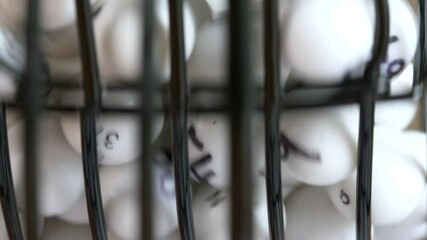 Extreme close-up of numbered balls spinning in a lottery or Bingo drum.