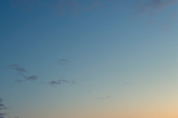 Gradient sunset sky with a few small gray clouds. Nature background image