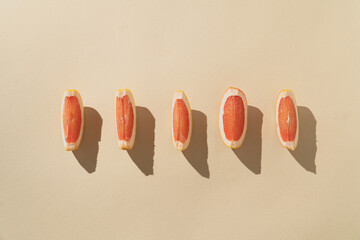 Slices of grapefruit arranged on a beige background. Fresh citrus fruit.