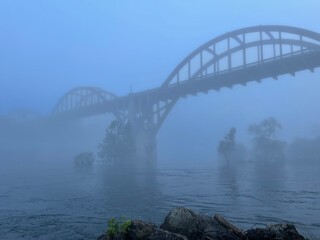 Fototapeta na wymiar Rainbow Arch Bridge over the White River in Cotter, Arkansas in the early morning fog - horizontal