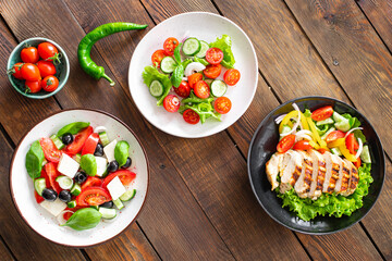 different salads vegetables, grilled chicken breast, olives, feta, tomato, onion, cucumber other on the table, healthy food