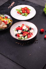 different salads vegetables, grilled chicken breast, olives, feta, tomato, onion, cucumber other on the table, healthy food