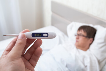 A sick grandmother temperature is checked. First aid.